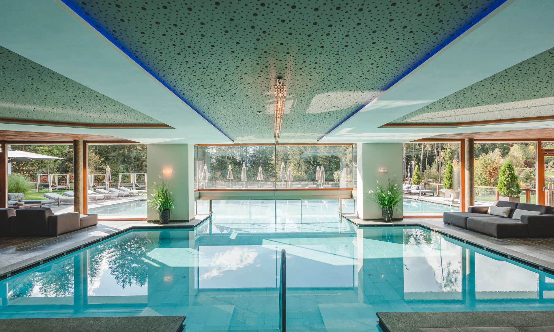 Entschleunigen und genießen in diesem Hotel nahe Bruneck Hallenbad mit Glasfront und Blick auf Außenpool und Liegestühle