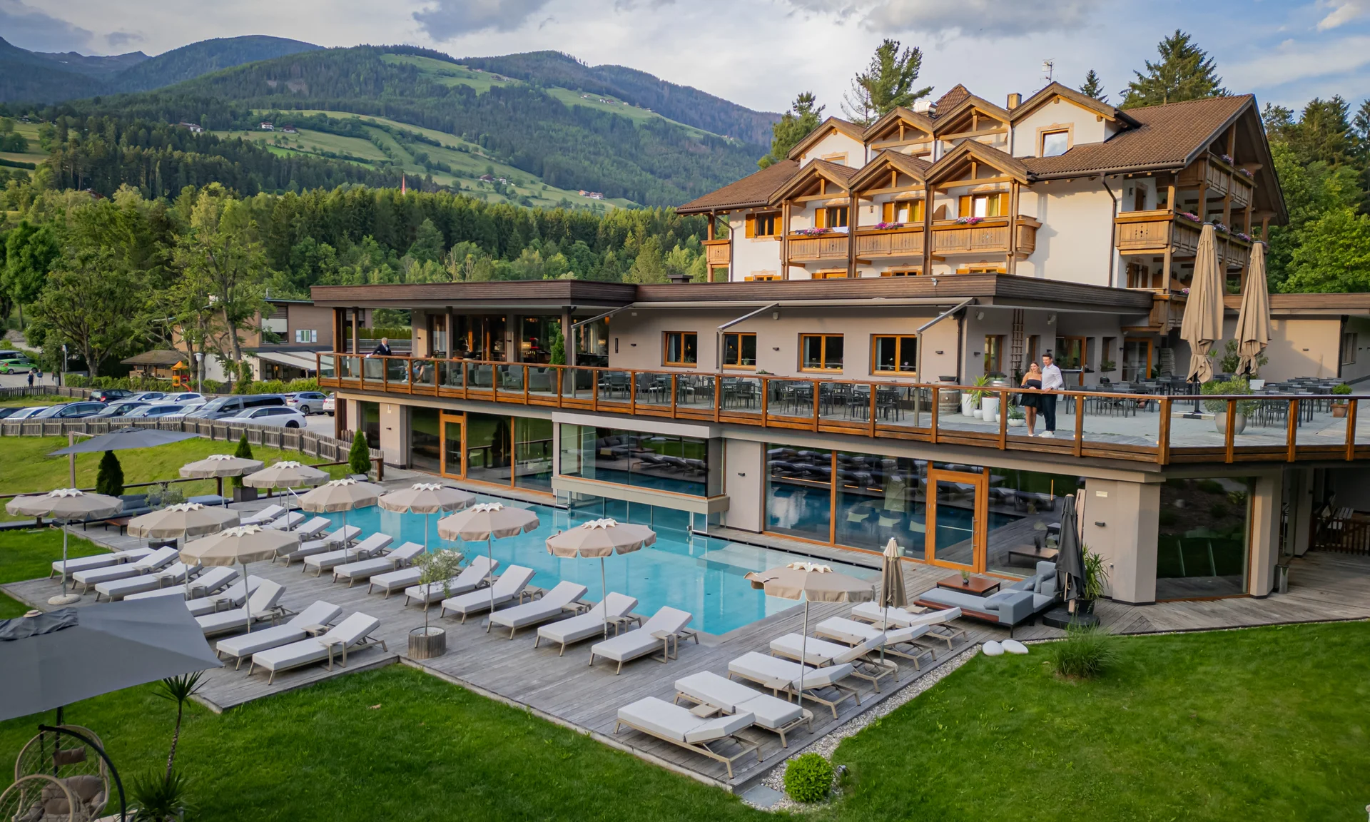 Entschleunigen und genießen in diesem Hotel nahe Bruneck Hotel mit Außenpool, Liegestühlen und Bergen im Hintergrund