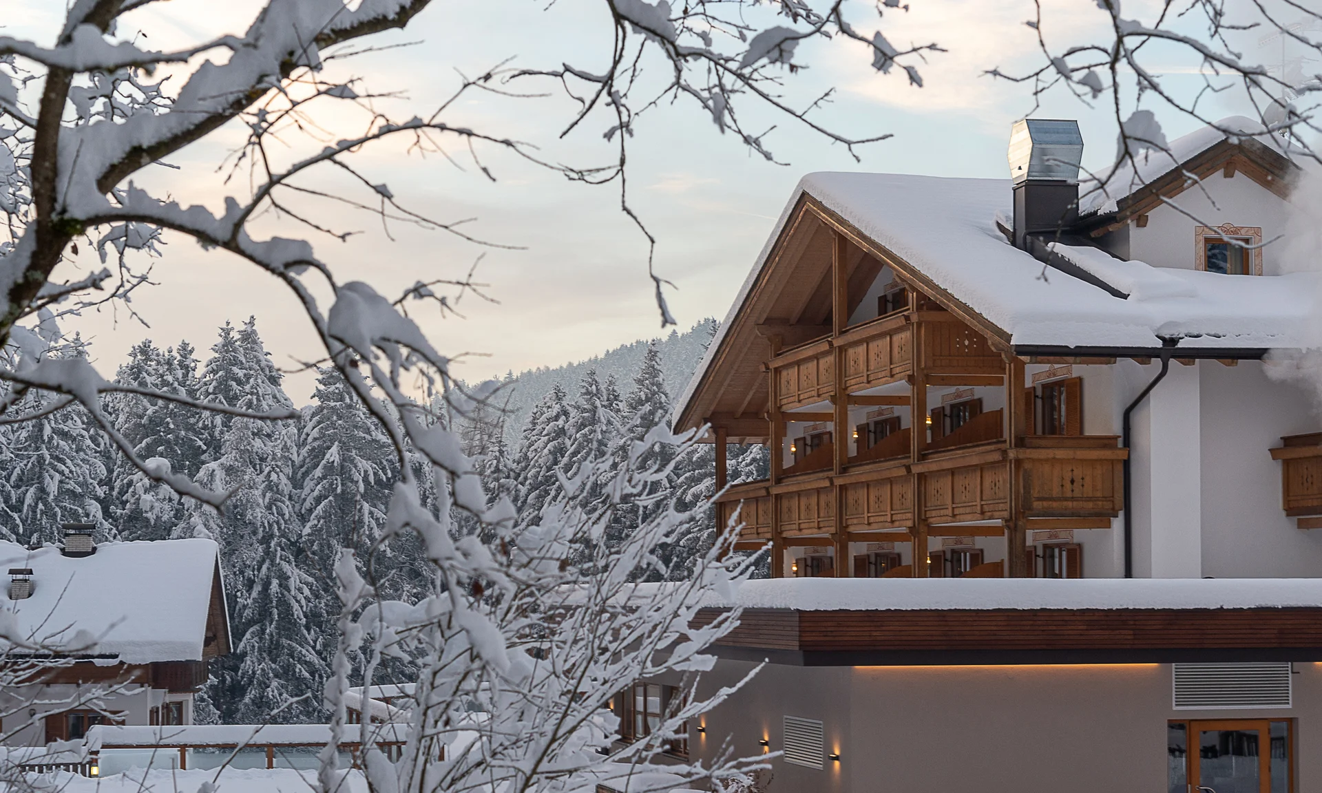 Entschleunigen und genießen in diesem Hotel nahe Bruneck Verschneites Hotel mit Holzbalconies in winterlicher Waldlandschaft