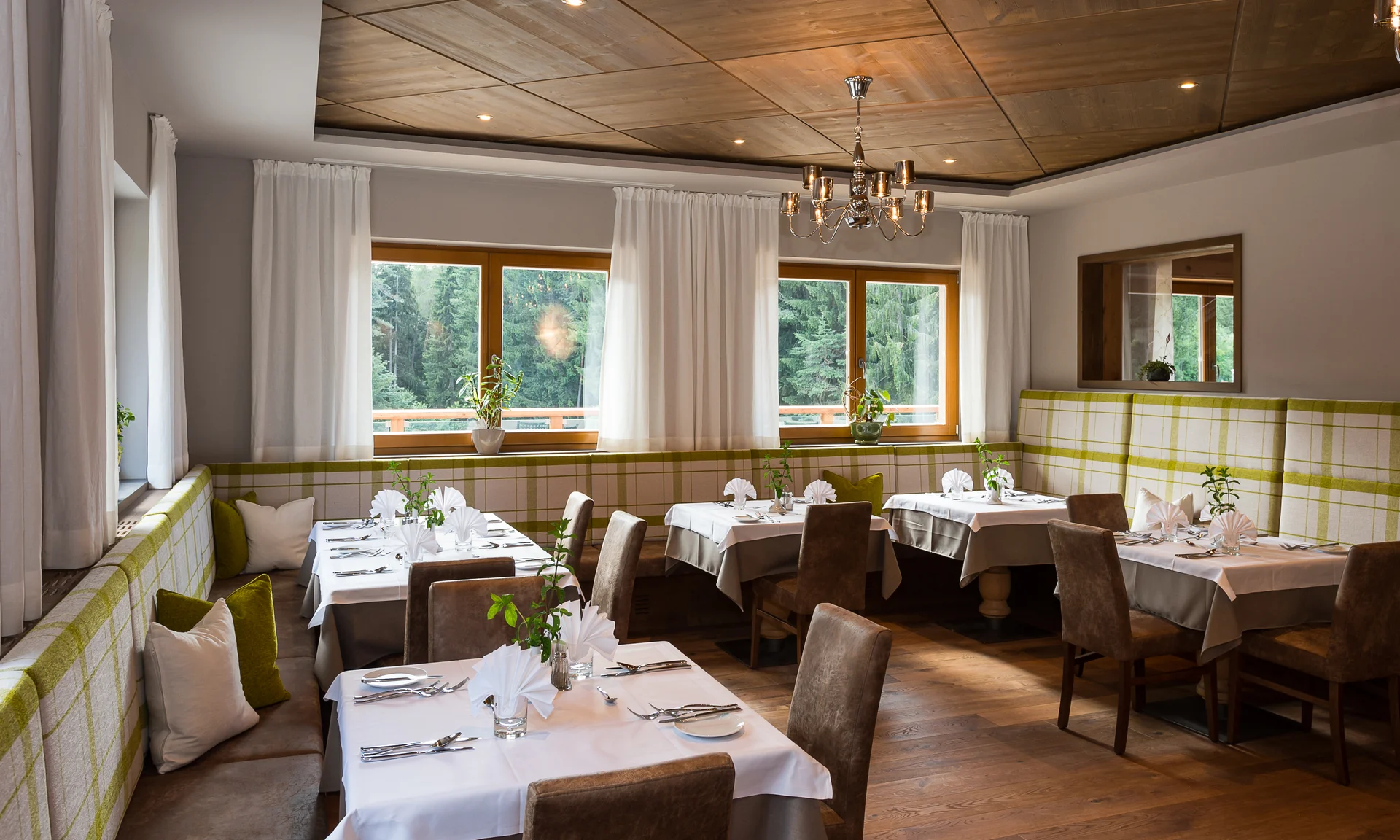 Entschleunigen und genießen in diesem Hotel nahe Bruneck Gemütlicher Speiseraum mit gedeckten Tischen und grünen Akzenten
