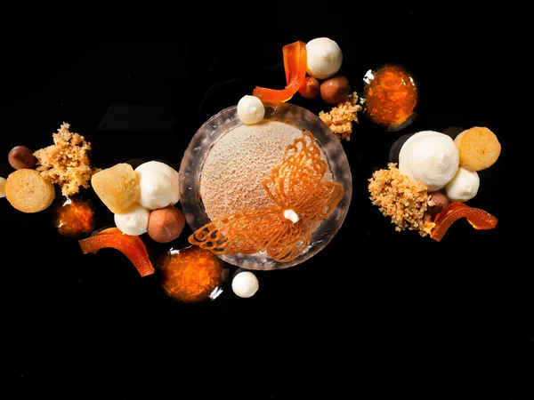Entschleunigen und genießen in diesem Hotel nahe Bruneck Kunstvoll angerichtetes Dessert mit Schmetterlingsdekor auf schwarzem Hintergrund