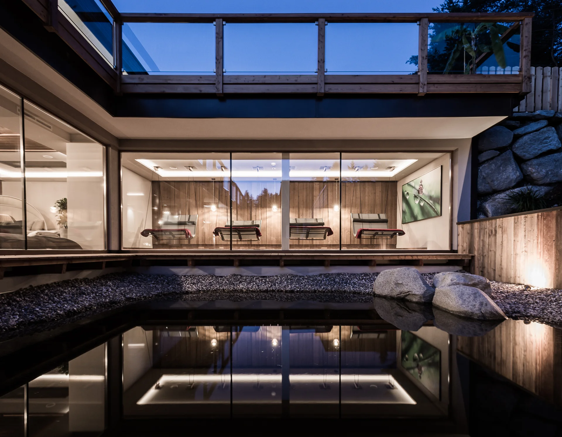 Entschleunigen und genießen in diesem Hotel nahe Bruneck Moderne Lounge mit Liegestühlen und Glasfront mit Blick auf Teich