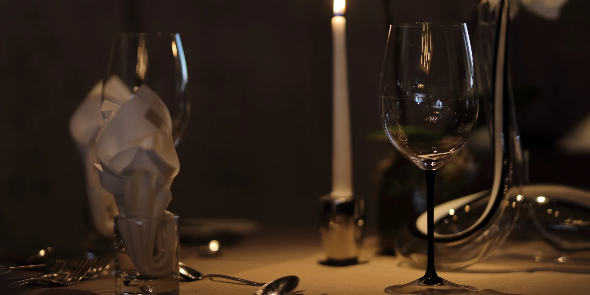 Entschleunigen und genießen in diesem Hotel nahe Bruneck Romantisch gedeckter Tisch mit Kerze, Weingläsern und Servietten